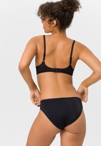 Schwarzes Lingerie-Set aus glattem, eleganten Stoff. Der BH hat verstellbare Träger und einen Hakenverschluss; die Panties haben ein schlichtes, tief ausgeschnittenes Design.