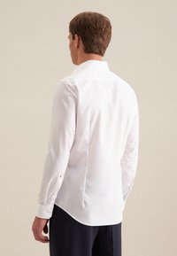 Weißes Hemd mit langen Ärmeln, taillierter Passform, runder Hemdsaum und Ein-Knopf-Manschetten. Glattes Baumwollgewebe mit klassischem Kragen.