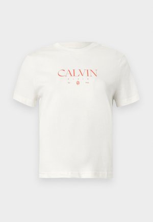 Valge puuvillane T-särk, mille keskel on punane "CALVIN KLEIN" logo, asutamise kuupäev, lühikesed varrukad ja klassikaline ümarsärk kaelus.