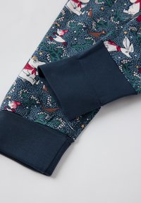 Patterned fabric featuring whimsical characters, predominantly in white and red on a dark blue background. Soft material with ribbed navy cuffs.