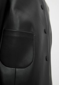 Schwarze Lederjacke mit einer Patten-Tasche, glatter Textur, geknöpftem Verschluss und tailliertem Design.