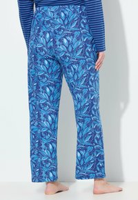 Blauwe gemusterde katoenen broek met een bloemenpatroon in verschillende tinten blauw en lichte accenten, wijde pijpen en een elastische tailleband.