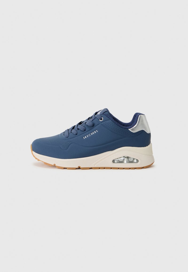 Baskets de sport bleues avec un dessus en synthétique lisse, des détails perforés et une semelle intermédiaire blanche. Comprend une unité de coussin d'air visible et une semelle en caoutchouc.