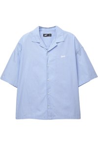 Camicia a maniche corte, con bottoni, di colore azzurro chiaro con strisce verticali bianche. Presenta un colletto con scollatura a V e un piccolo logo ricamato sul petto.