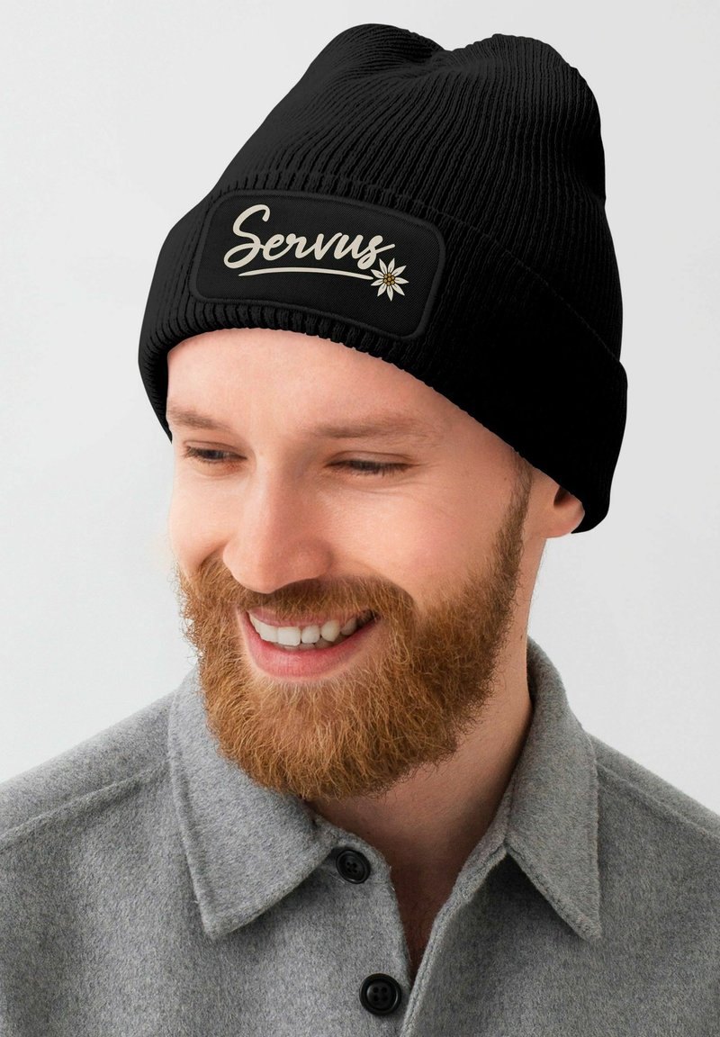 Black ribbed beanie with a rectangular patch displaying the text "Servus" in white script and a small floral design.