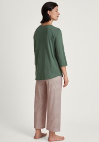 Maglia verde menta a maniche lunghe abbinata a pantaloni da pigiama a culisse con motivo a diamante rosa e bianco. Tessuto morbido e leggero, design rilassato.