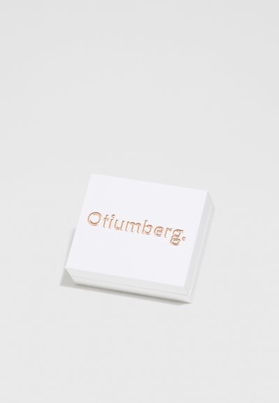 Balts taisnstūra kastīte ar izspiestu rozā zelta "Ofiumberg." logo uz augšas. Gluda virsma, gaiši stūri, minimālisma dizains.