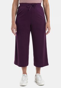 Lila, korta byxor med elastisk midja och dragsko. Tillverkade av mjukt material, med en avslappnad passform och sidfickor.