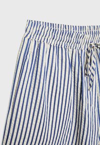 Cotton shorts with a textured, crinkled finish, featuring blue and white vertical stripes, elastic waistband, and a drawstring closure.