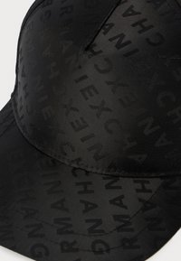 Casquette de baseball noire avec un motif en relief répété du mot "ARMANIEXCHANGE" sur le tissu.