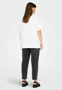 Witte katoenen t-shirt met korte mouwen, voorzien van oogjesdetails. Gepaard met donkergrijze denim broek en zwarte chunky sandalen.