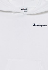Sudadera blanca con capucha hecha de material de felpa. Cuenta con un bolsillo frontal y el logo bordado en navy "Champion" en el lado izquierdo del pecho.