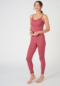 Top con scollo a pizzo rosa, aderente, abbinato a leggings coordinati. Tessuto morbido, senza motivi visibili, e orli delle caviglie in pizzo.