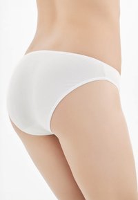 Slip in cotone bianco con una superficie liscia, design a vita media e sottili dettagli laterali. Bordo seamless per una vestibilità confortevole.