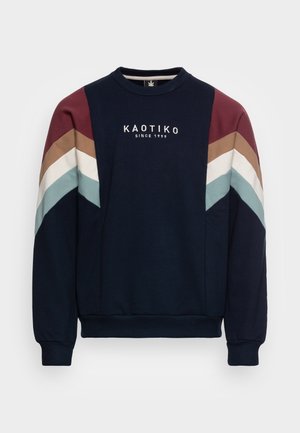 Granatowa bluza z dzianiny z prążkowanymi mankietami i krawędzią, wielokolorowymi paskami w kształcie litery V na rękawach oraz napisem "KAOTIKO SINCE 1999" na piersi.