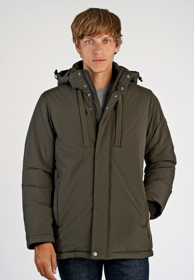 Olivenfarvet isoleret jakke med hætte, lynlås foran og trykknaplukning. Har store lommer og en blød overflade.