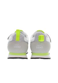 Šedé a bílé tenisky s lesklým stříbrným zadním dílem, neonově zelenými akcenty a bílou mezipodešví s nápisem "SINCE 1890" vytištěným na patě.