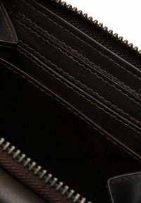 Interno di un portafoglio in pelle nera con più slot per carte, cuciture raffinate e chiusura con zip. Foderato con tessuto testurizzato.