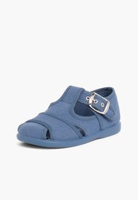 Sininen kangassandaali, jossa on avoin varvasosa, hihnasuunnittelu ja metallinen solki. Litteä pohja ja teksturoitu päällinen, jossa on ristiin hihnat turvallista istuvuutta varten.