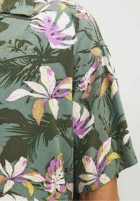 Kortärmad, grön blommig skjorta med rosa, vita och gula blommönster, tillverkad av mjukt tyg med en avslappnad passform.