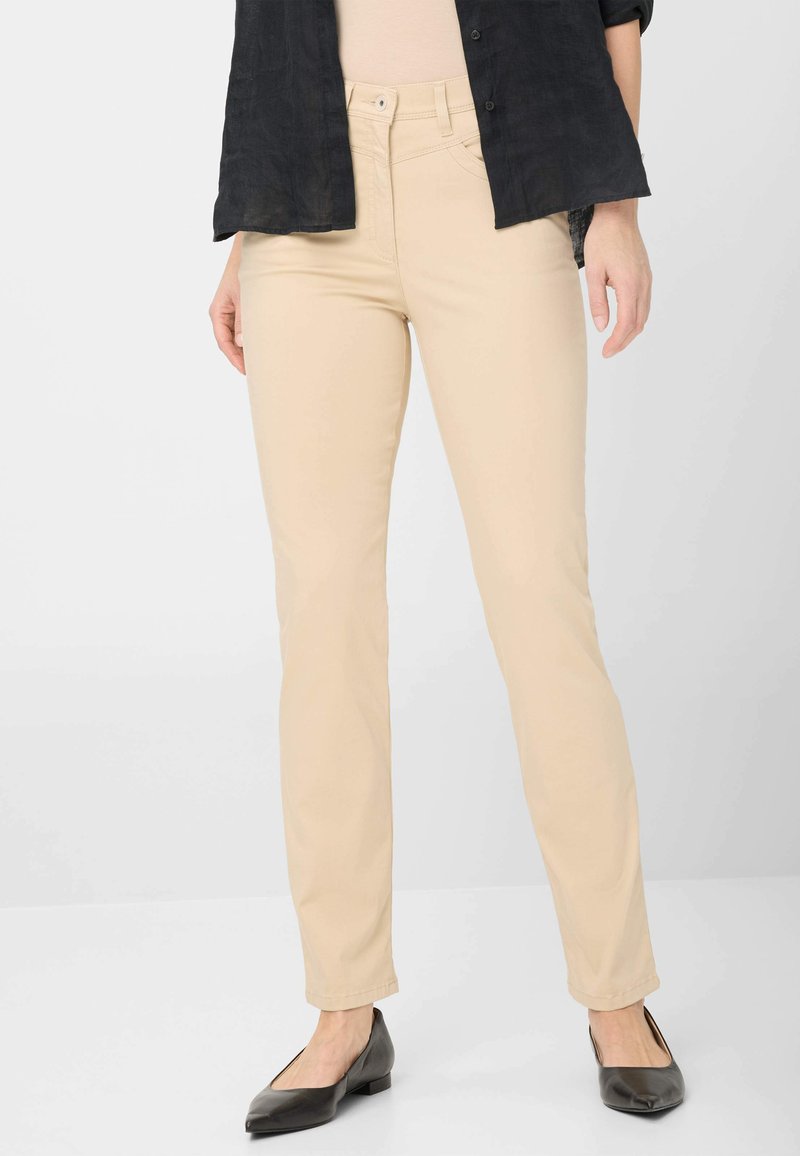 Pantalon slim beige en mélange de coton, avec un design classique à 5 poches, des passants de ceinture et des détails de couture subtils. Assorti avec des ballerines noires.