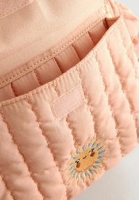 Quilted pink fabric bag interior featuring a small sun embroidery. Includes a smooth pocket with a hook and loop closure.