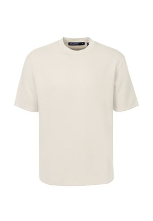 Effen beige T-shirt met korte mouwen en ronde hals met een klein reliëflogo nabij de onderzoom, afgebeeld op een witte achtergrond.