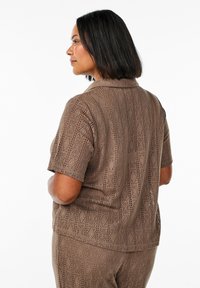 Bruine overhemd met korte mouwen in opengebreide stof met ruitpatronen. Het shirt heeft een kraag en is ontworpen voor een ontspannen fit.