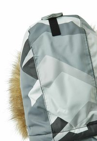 Szara wzorzysta zimowa czapka z ozdobnym futerkiem. Charakteryzuje się eleganckim designem i paskiem na rzep na górze. Gładka faktura z geometrycznymi kształtami.