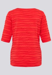 Rotes Kurzarmoberteil mit einem strukturierten, wellenförmigen Design. Der Stoff ist leicht, hat eine lockere Passform und einen runden Ausschnitt.