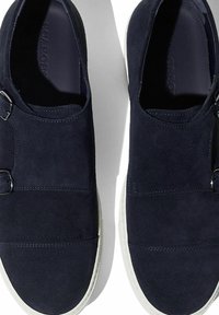 Tamno plavi suknjani slip-on cipele s dvostrukim kopčama, bijela gumena potplata, glatka tekstura i šivani detalji na gornjim panelima.