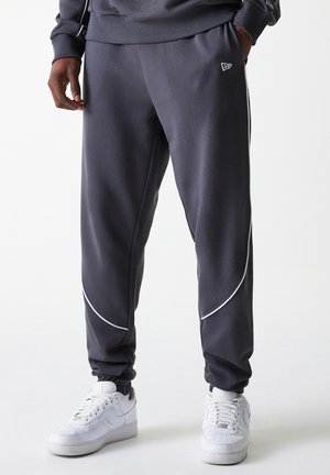 Dark gray athletic pants with white piping accents, cuffed at the ankles, made of soft material. Worn with white sneakers.