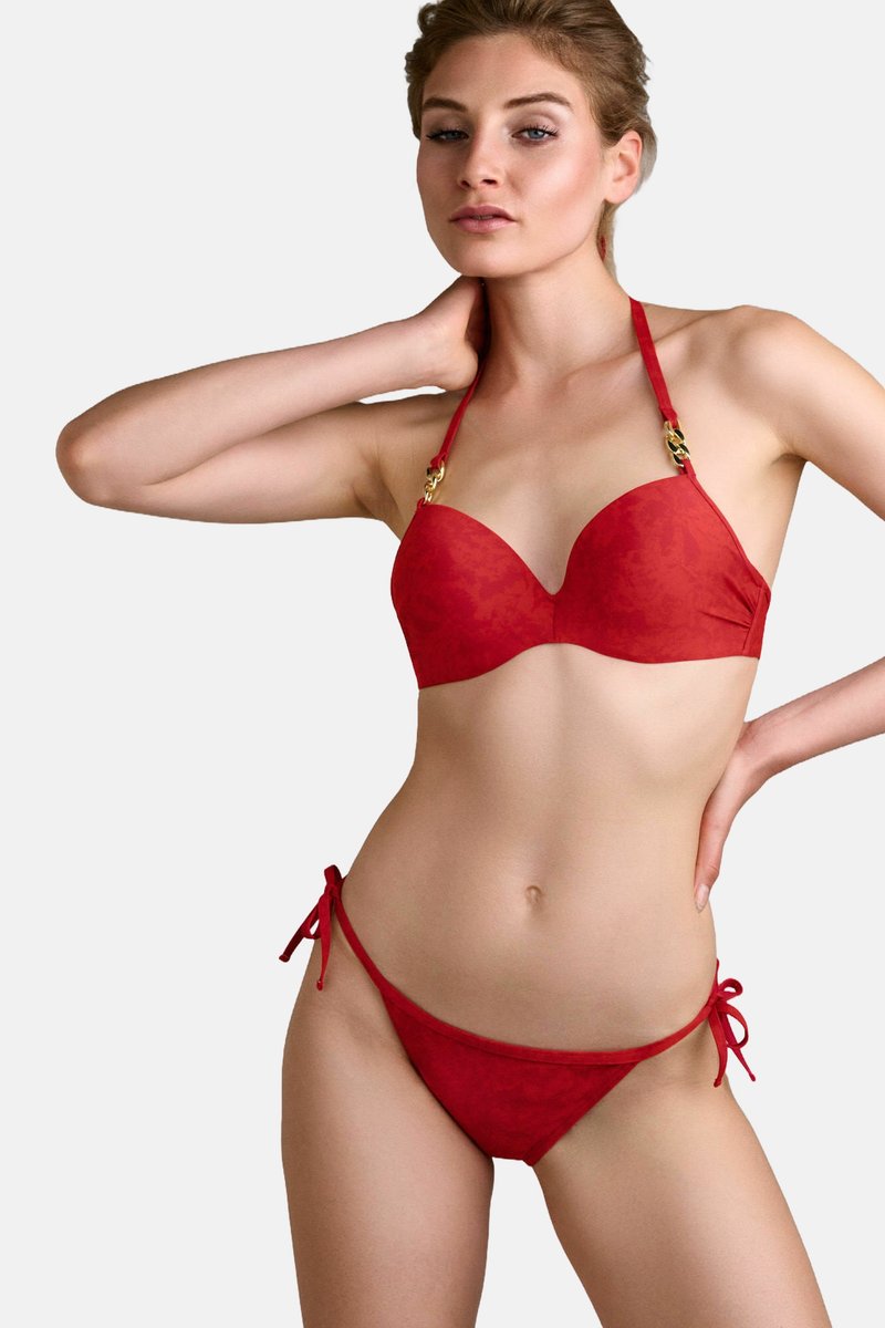 Červený bikiny set s formovaným, vycpaným bikinovým topem, který obsahuje dekorační kovové prvky a nastavitelné ramínka. Spodní díl má boční šňůrky a hladký povrch.