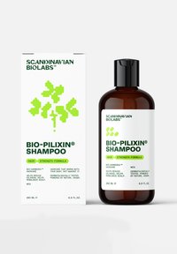 Bouteille de shampoing marron avec un capuchon noir et une étiquette blanche. Le texte vert indique "BIO-PILIXIN® SHAMPOO." La boîte blanche présente un design de feuille verte et des informations sur le produit.