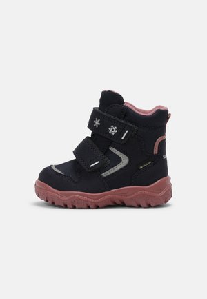 Botte d'hiver enfant noire et rose avec deux sangles Velcro, motifs flocons de neige, semelle robuste et étiquette Gore-Tex sur le côté.