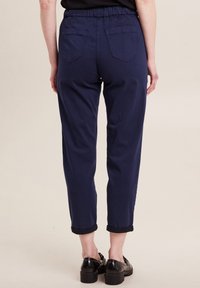 Navyblauwe, relaxte broek met een elastische tailleband, omgeslagen manchetten en twee achterzakken; gladde katoen stof.
