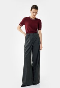 Top de punto burdeos de manga corta con ribete blanco, combinado con pantalones gris de pierna ancha de alta cintura que cuentan con un elegante lazo y una tela suave.