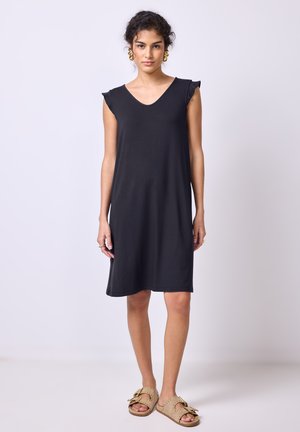 Schwarzes knielanges Kleid mit kurzen Ärmeln, V-Ausschnitt und glatter Textur. Kombiniert mit hellbraunen Riemchensandalen mit dekorativen Akzenten.
