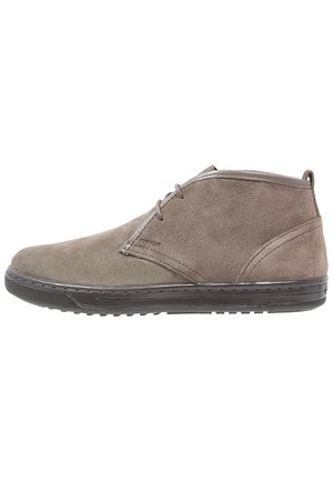 Chaussure décontractée mi-haute en suède marron pour homme avec lacets sur le devant et semelle en caoutchouc foncé, vue de profil sur fond blanc.