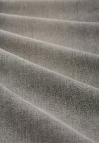 Szürke szövet sima textúrával, átlós redőkkel és finom szőtt mintával, közepes súllyal és puha felülettel.