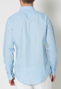 Hellblau kariertes Hemd mit langen Ärmeln, Kentkragen und Knopfdetails an den Manschetten. Glattes Baumwollmaterial, abgerundeter Saum.