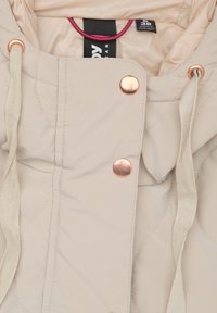 Beige gewatteerde jas met capuchon, bronzen drukknoopsluitingen en textiel met bijpassende trekkoorden. Voering is lichtroze.