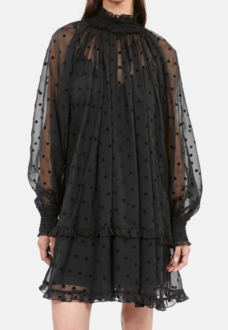 Schwarzes Kleid aus transparenter Stoff mit Polka-Dots, ausgestattet mit einem hohen gerafften Kragen, langen Ärmeln und Rüschen am Saum.
