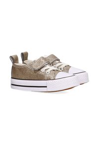 Zapatillas de lona metálicas doradas con suelas de goma blancas, punteras redondeadas y doble cinta de velcro. Una franja negra a lo largo de la suela añade un contraste.