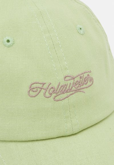 Green cotton cap with light pink embroidered “Holyweiler” logo, structured design, visible stitching, and textured fabric.