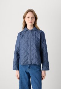 Gequilted marineblauwe jas met diagonale strepen, vier knopen, een kraag en manchet mouwen. Zachte textuur met een relaxte pasvorm.