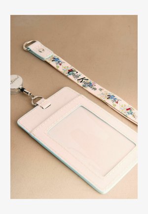 Držák průkazky a šňůrka na krk. Držák je bílý s světle modrými okraji a má průhledné okénko; šňůrka má květinový vzor a logo.