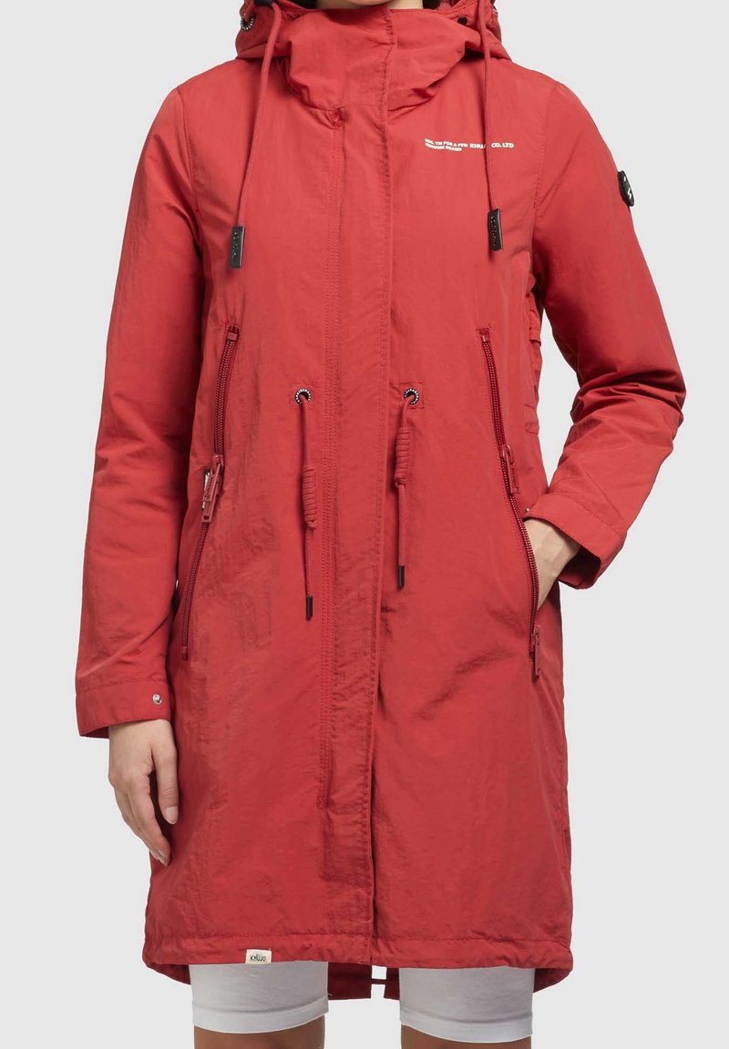 Red long waterproof jacket with a hood, adjustable drawstrings, front zip pockets, and logo accents. Smooth texture, relaxed fit.