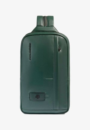 Zaino in pelle verde dalla texture liscia, design sottile, due cerniere e una tasca frontale con una discreta patch con il logo.