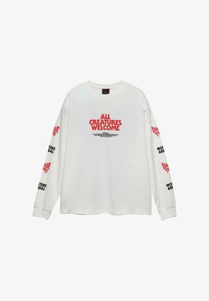 Fehér, hosszú ujjú ing, amelyen piros "MINDEN LÉNY ÜDVÖZÖLT" felirat található a mellrészen, és fekete-piros "STRANGER THINGS" és "A SZÖRNYEK VALÓDIK" feliratok az ujjakon.